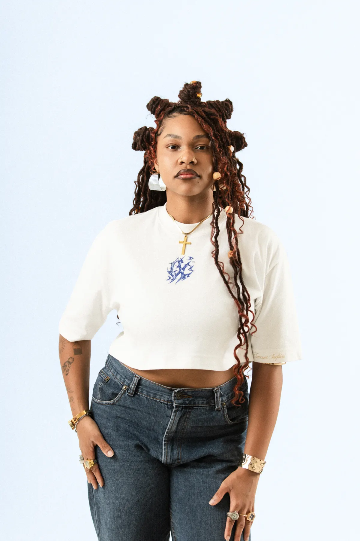 Modelo de tranças com coques, de frente, com o cropped branco e calça jeans.
