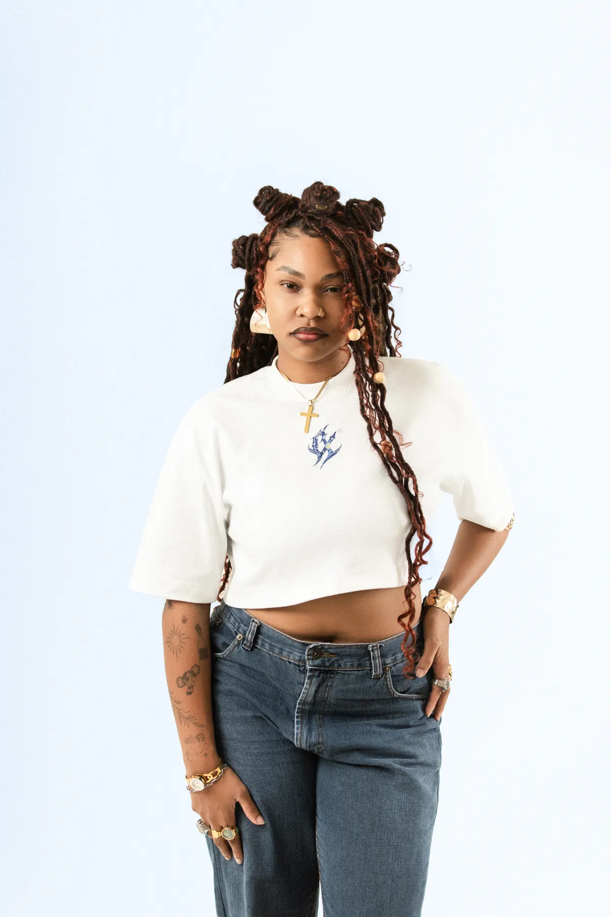 Modelo de tranças com coques, de frente, com o cropped branco e calça jeans.
